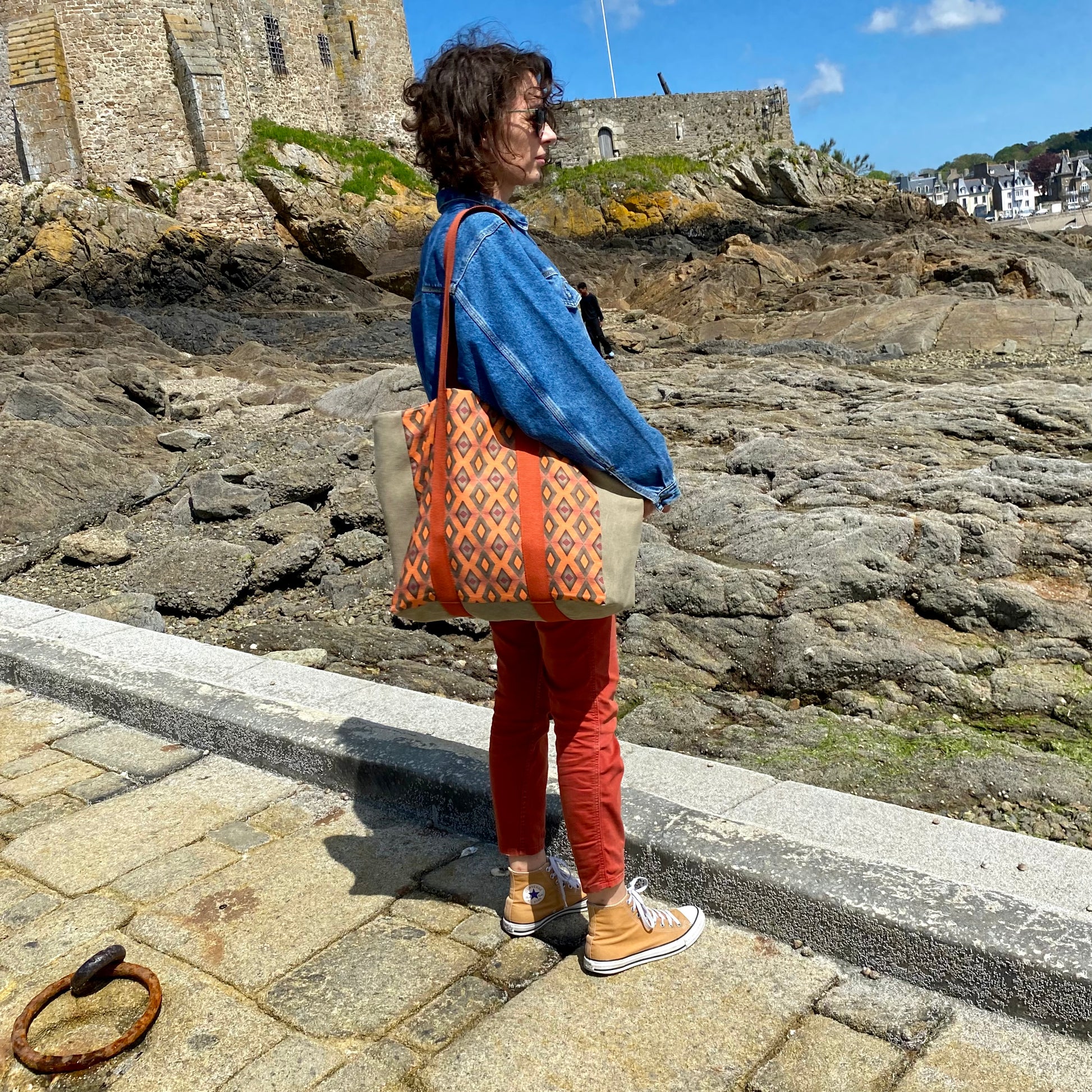 [html] <img src= »grand-cabas-frehel-vue-sur-motif-frehel-et-sangle-couleur-brique-porte-epaule-modele-tee-veste-legere-bleu-ciel-et-jean-used-cale-solidor-saint-servan» /> [/html]